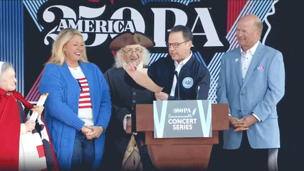 America250 backdrop collapses toward Pennsylvania Gov. Josh Shapiro and historical reenactors during Hershey concert announcement